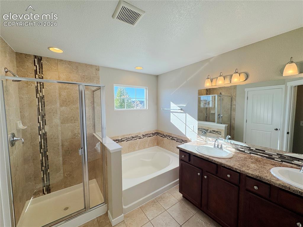 Image 33 of 42: Bathroom featuring a dual-sink vanity with dark-finish cabinetry, a built-i