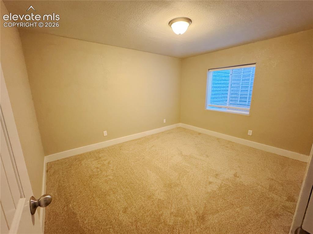 Image 37 of 42: Neutral-toned carpeted room featuring a single window and a central flush-m