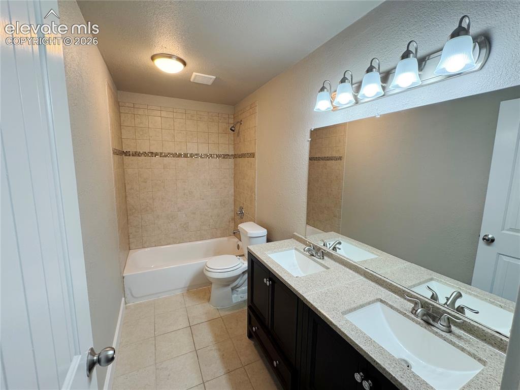 Image 38 of 42: Double vanity featuring a light-toned solid surface countertop with dual in