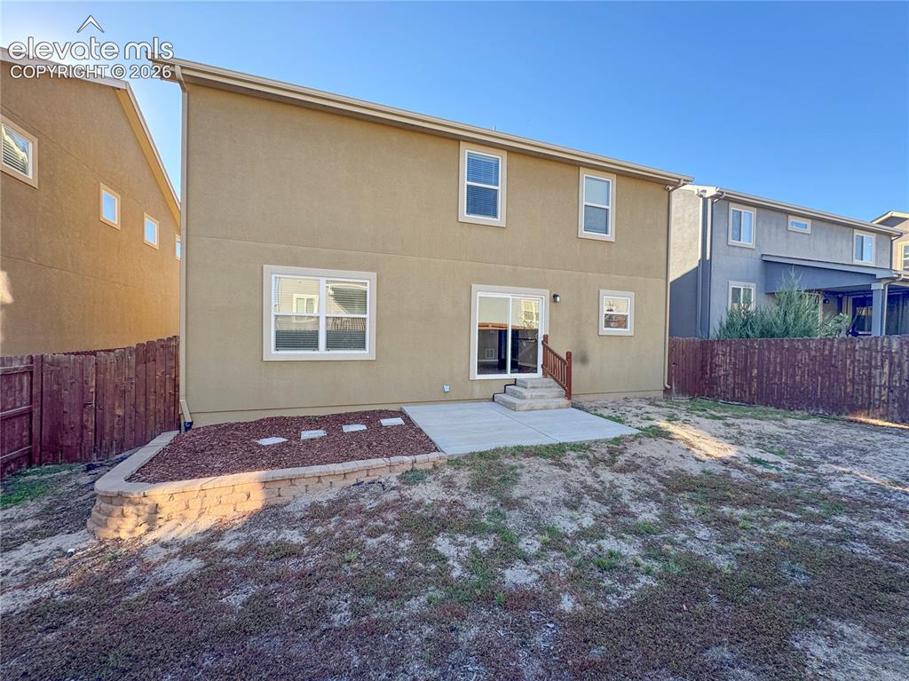 Image 40 of 42: Stucco exterior featuring a concrete rear patio, sliding glass door, tiered