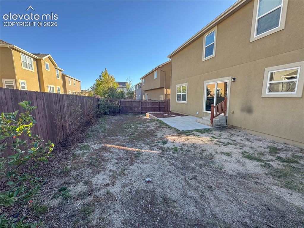 Image 41 of 42: Rear exterior featuring a fenced yard, concrete patio, sliding glass door,