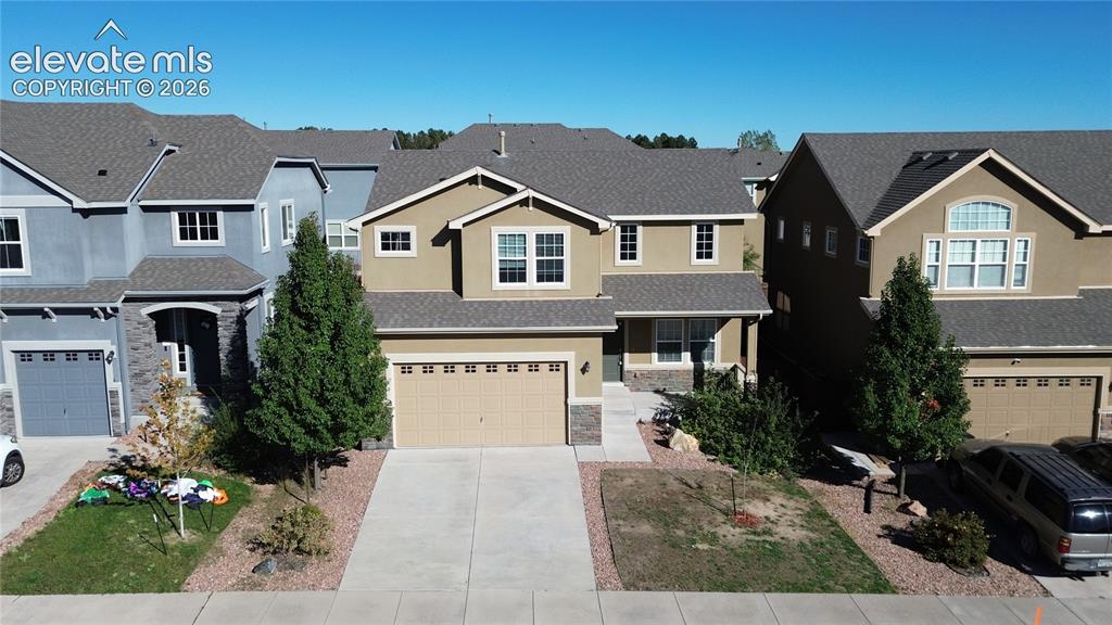 Image 42 of 42: Two-story exterior featuring a neutral stucco facade, stone veneer accents,