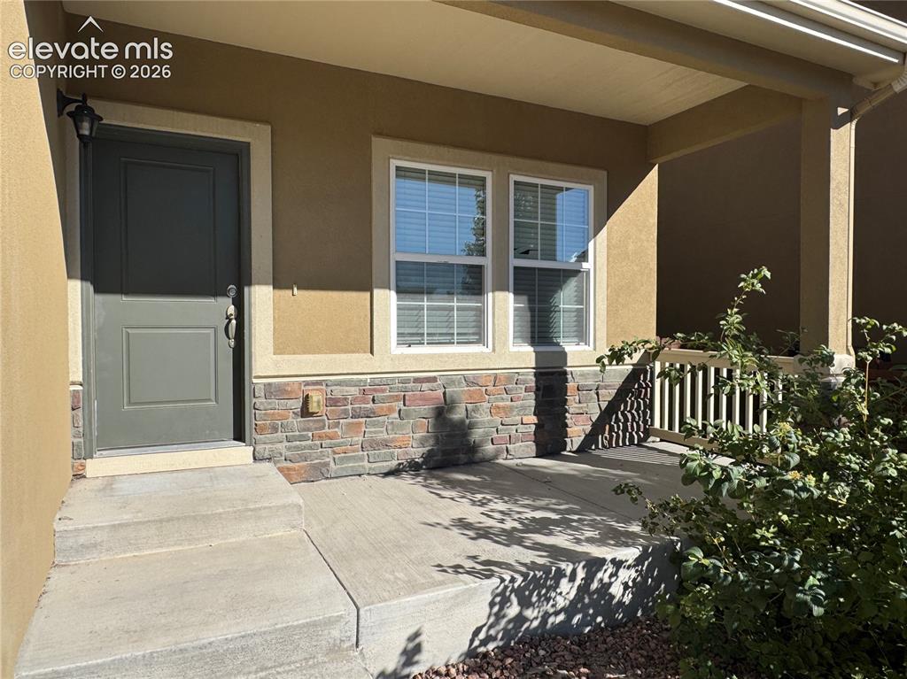 Image 6 of 42: Covered front porch featuring a concrete foundation, stone-veneer accent wa