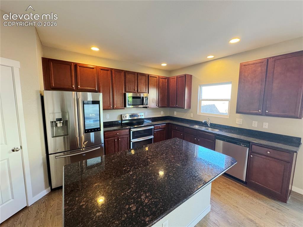 Image 9 of 42: Kitchen featuring dark-toned cabinetry, a spacious center island with stone