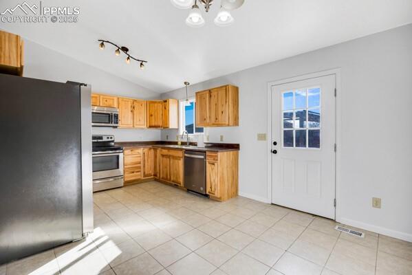 Image 12 of 26: Kitchen with stainless steel appliances, hanging light fixtures, dark count