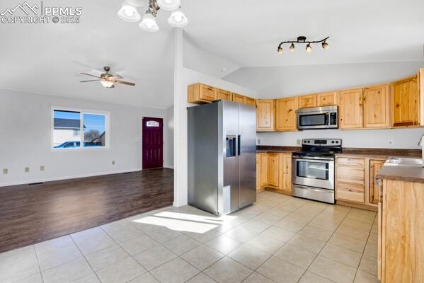 Image 13 of 26: Kitchen with light tile patterned floors, stainless steel appliances, dark 