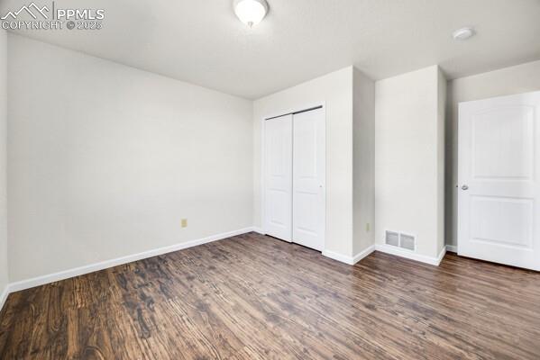 Image 17 of 26: Unfurnished bedroom with a closet and dark wood-style floors