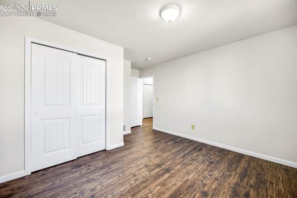 Image 18 of 26: Unfurnished bedroom featuring a closet and dark wood-style flooring