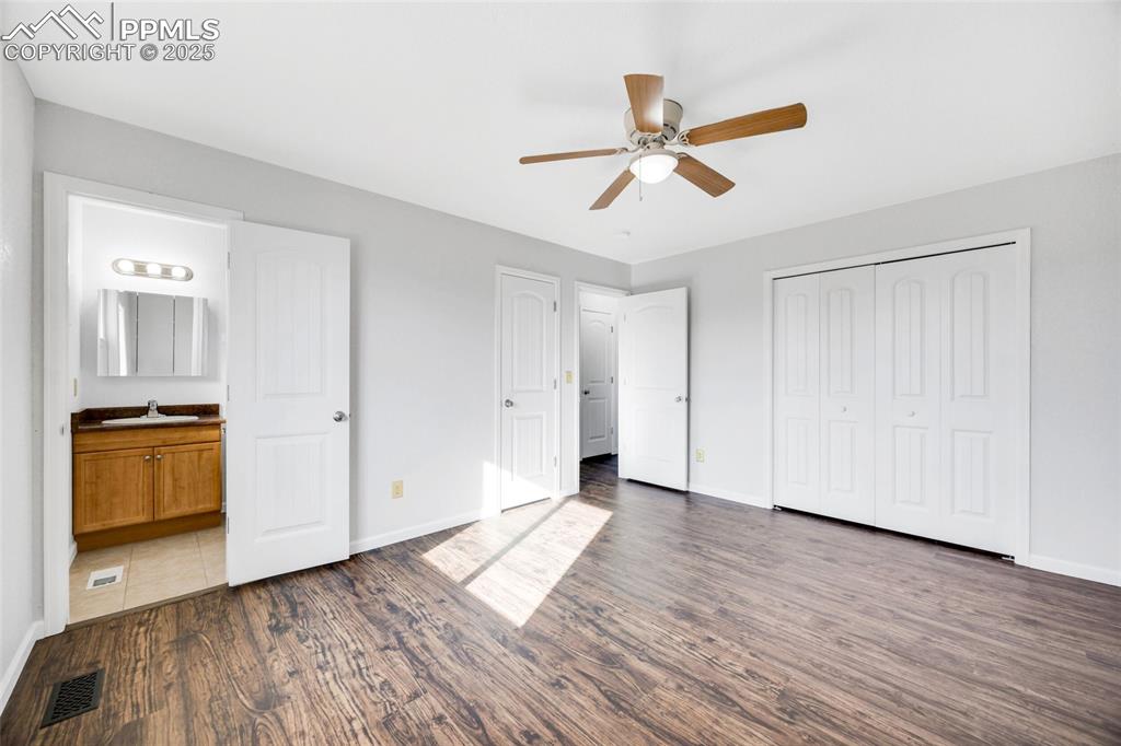 Image 9 of 26: Unfurnished bedroom with dark wood-style flooring, a ceiling fan, ensuite b