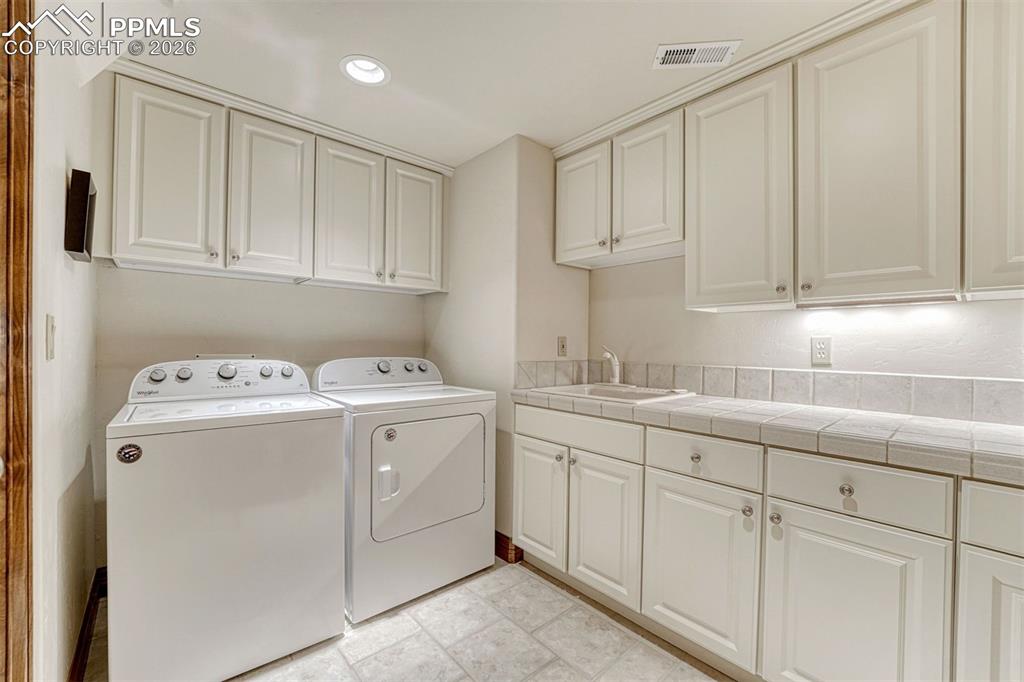 Image 38 of 50: Laundry room with abundant storage and upstairs connections ready for a sec