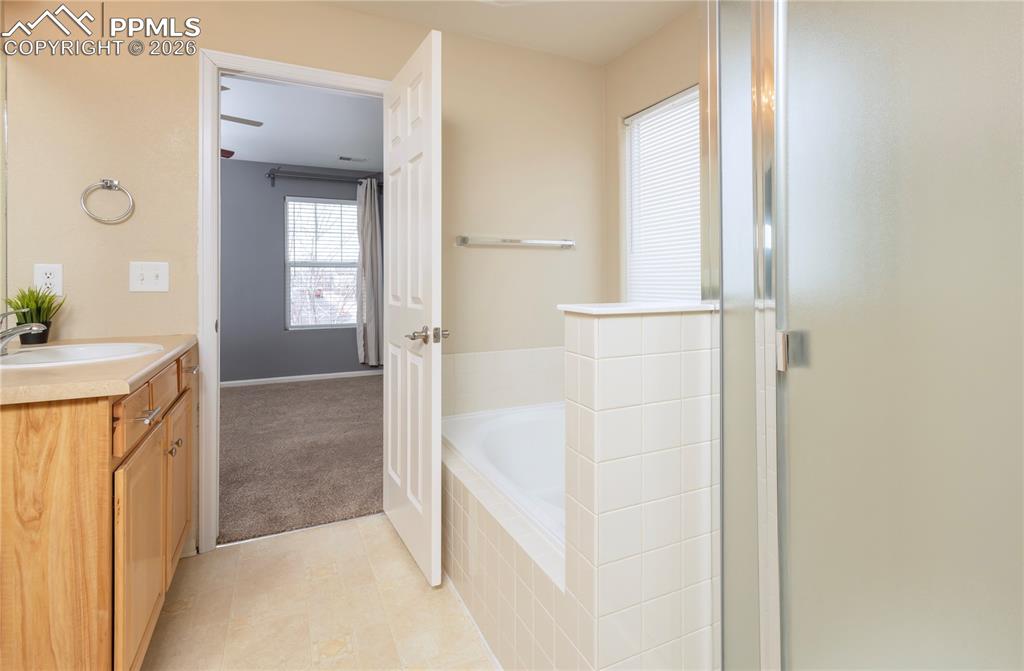 Image 14 of 33: Bathroom with vanity, a stall shower, a garden tub, and light tile patterne