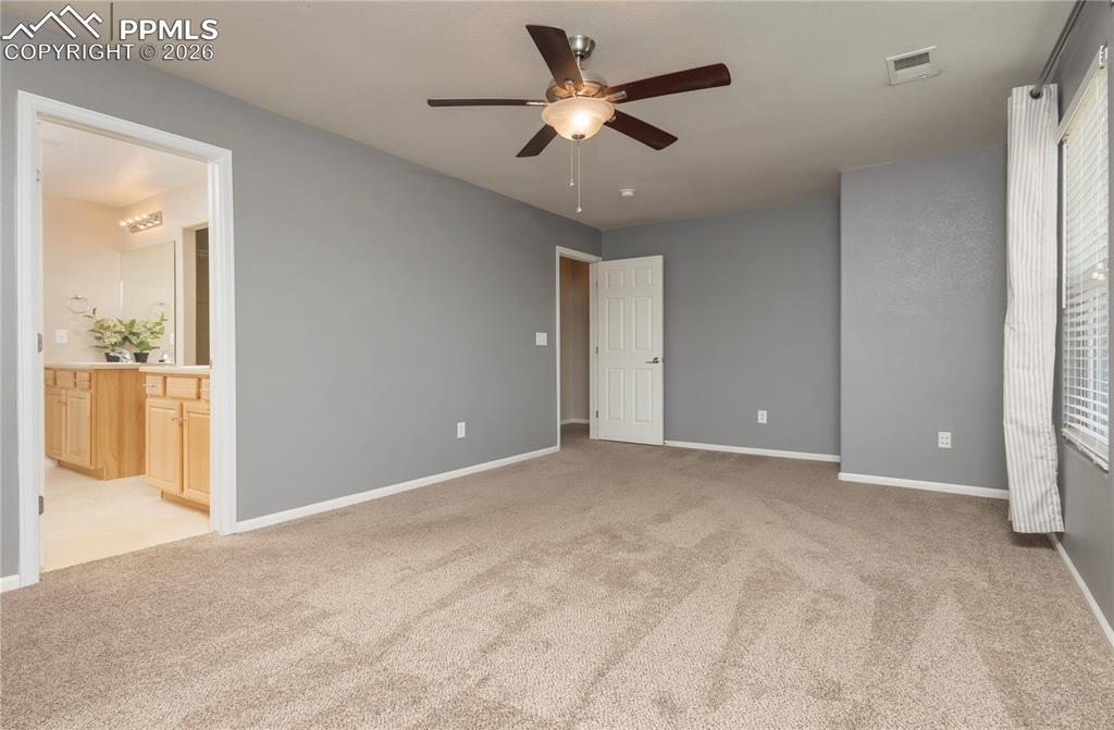 Image 24 of 33: Unfurnished bedroom with light colored carpet, ceiling fan, and ensuite bat