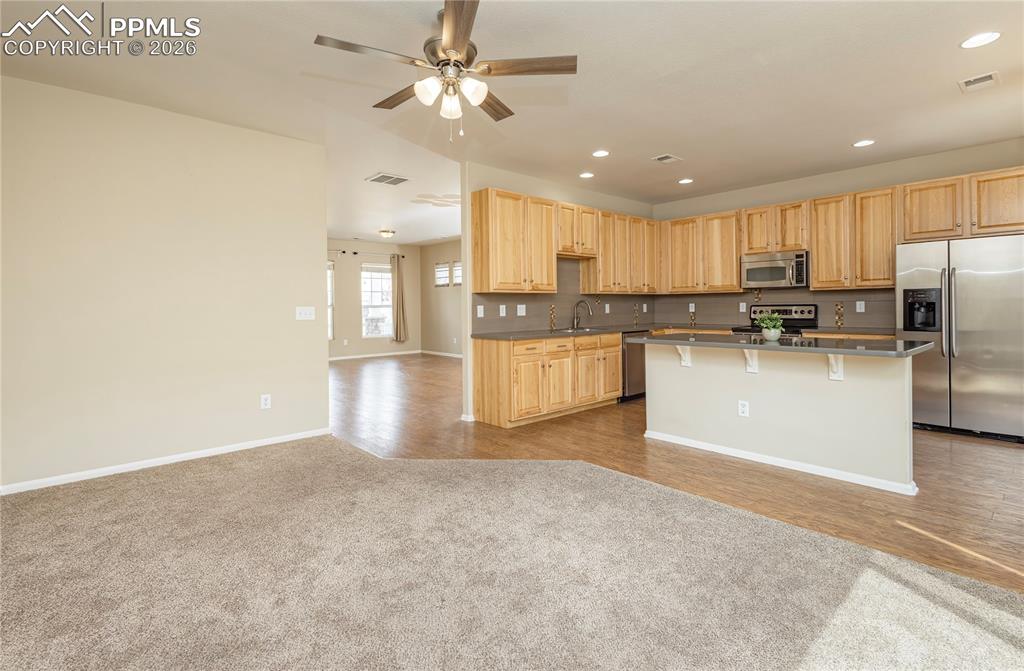 Image 28 of 33: Kitchen with stainless steel appliances, light wood finish cabinetry, open
