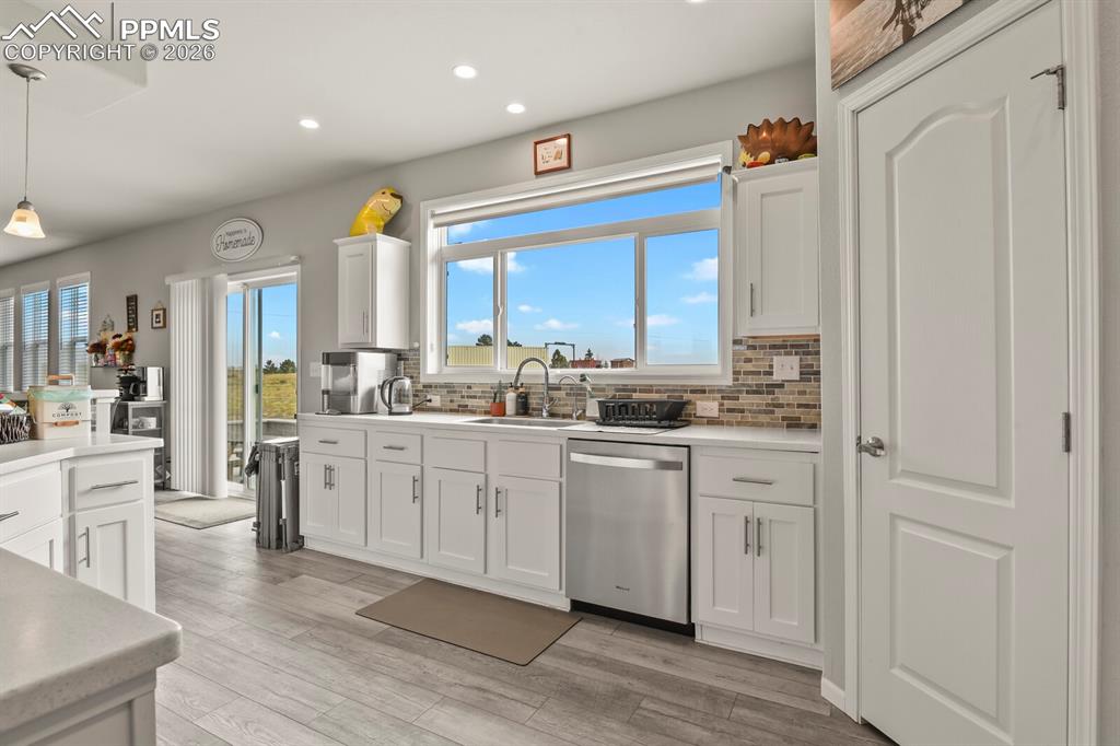 Image 10 of 48: Kitchen featuring white cabinetry, light-toned countertops, a multi-tone ti