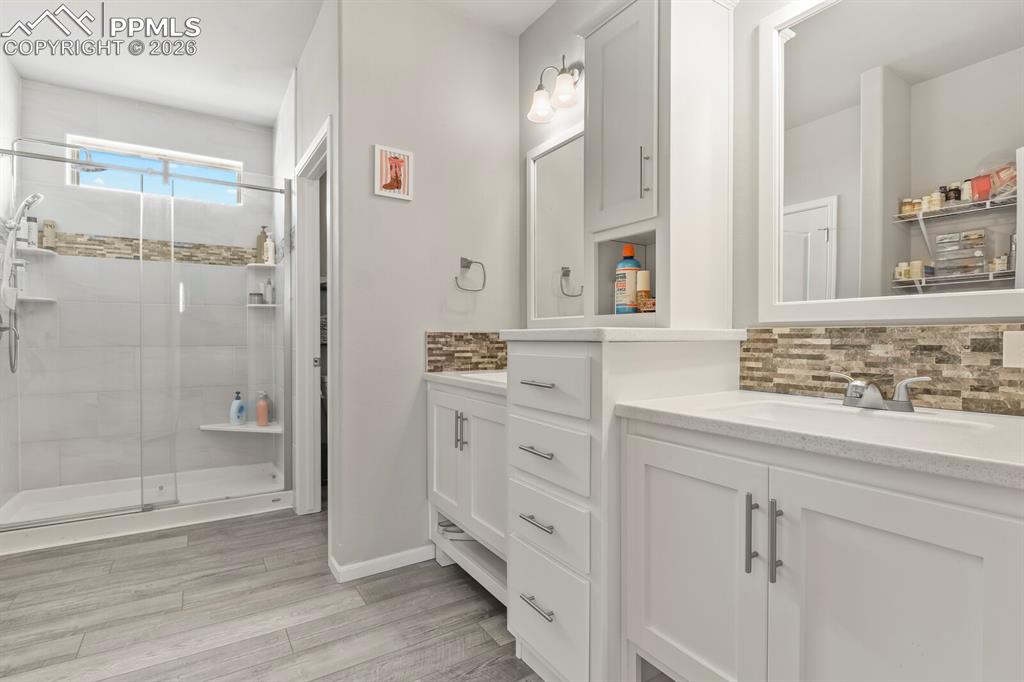 Image 20 of 48: Bathroom featuring a walk-in shower with glass enclosure, dual vanity sinks