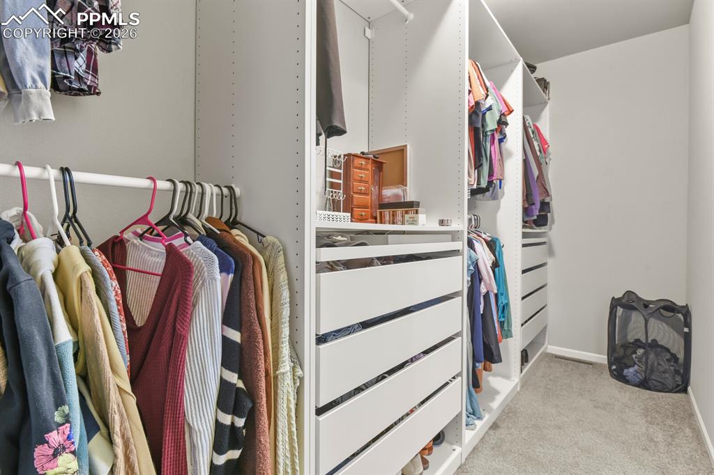 Image 21 of 48: Custom closet system featuring white cabinetry, multiple hanging rods, inte