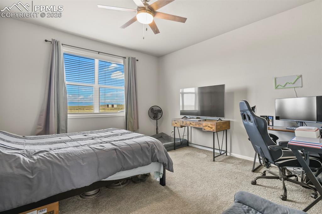 Image 22 of 48: Carpeted room featuring a large window with horizontal blinds, a ceiling fa