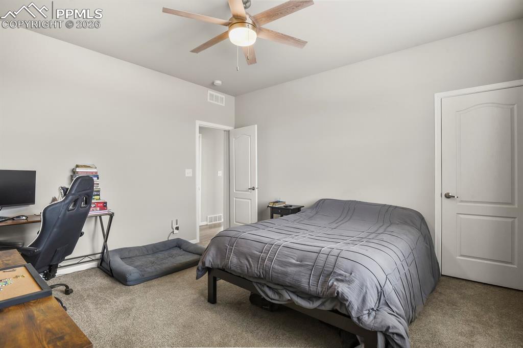 Image 23 of 48: Neutral-toned bedroom featuring a light wood-finish ceiling fan, recessed l