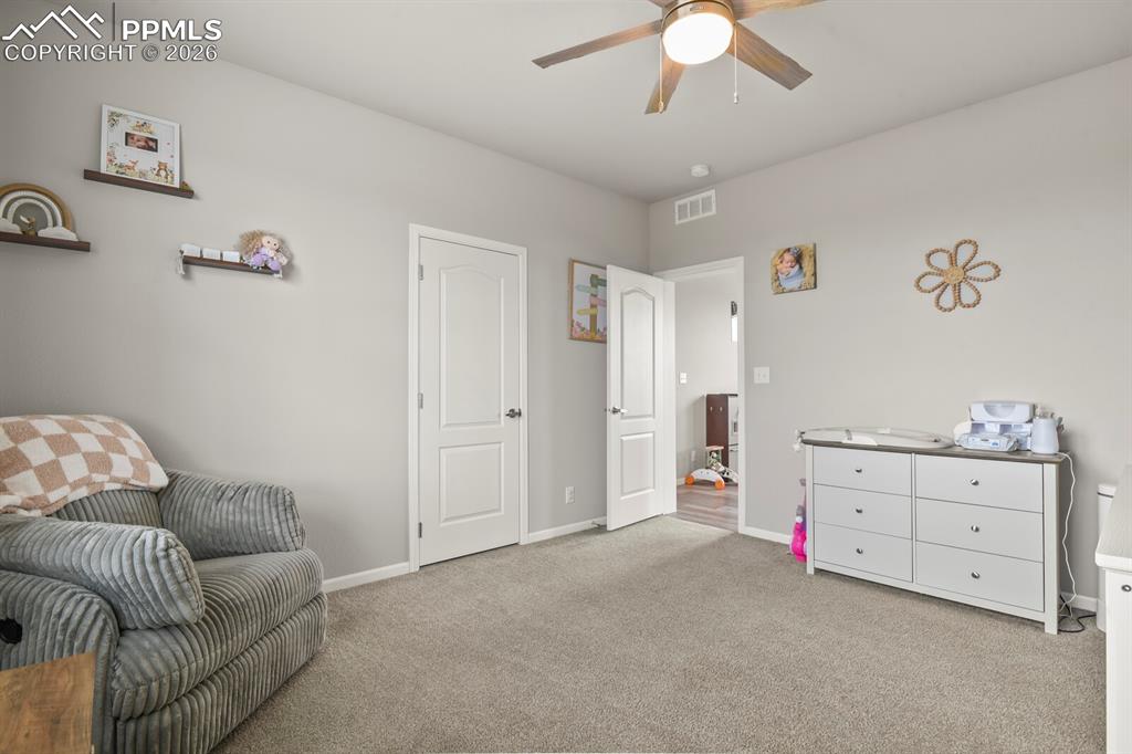 Image 26 of 48: Light gray wall paint with white trim, gray carpet flooring, ceiling fan wi