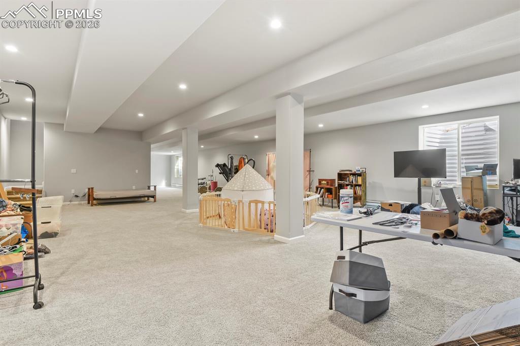 Image 28 of 48: Expansive carpeted lower level featuring recessed lighting, support columns