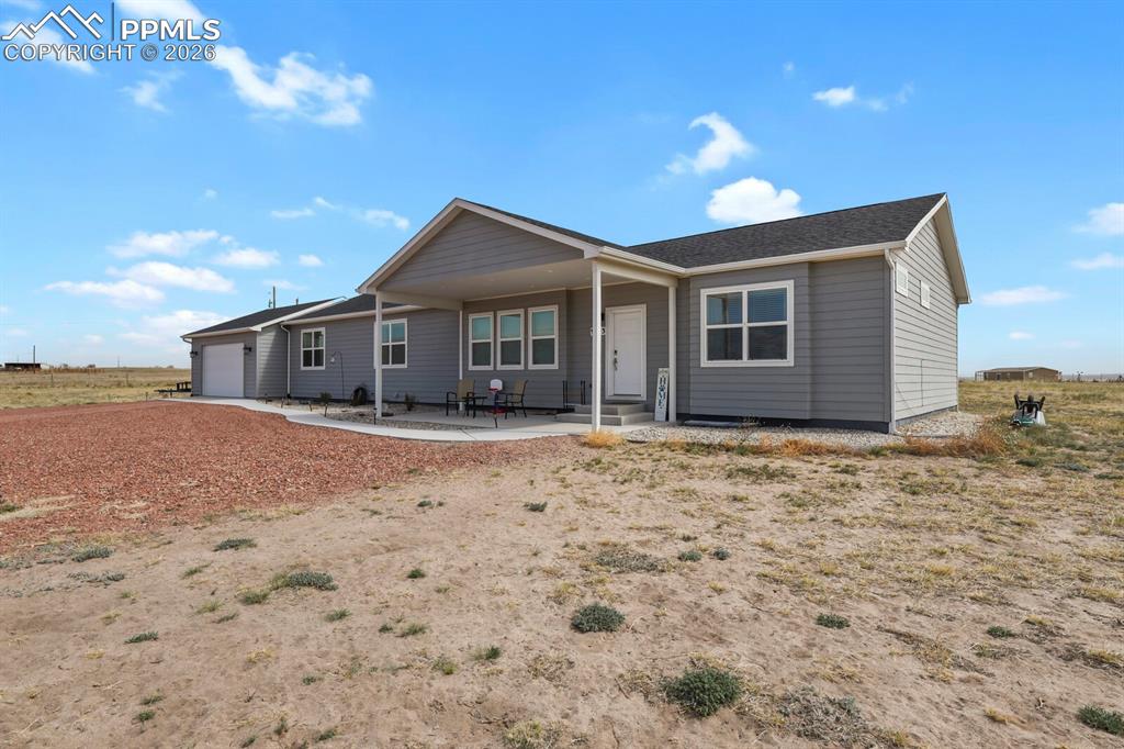 Image 3 of 48: Contemporary ranch-style home featuring gray horizontal siding, a covered f
