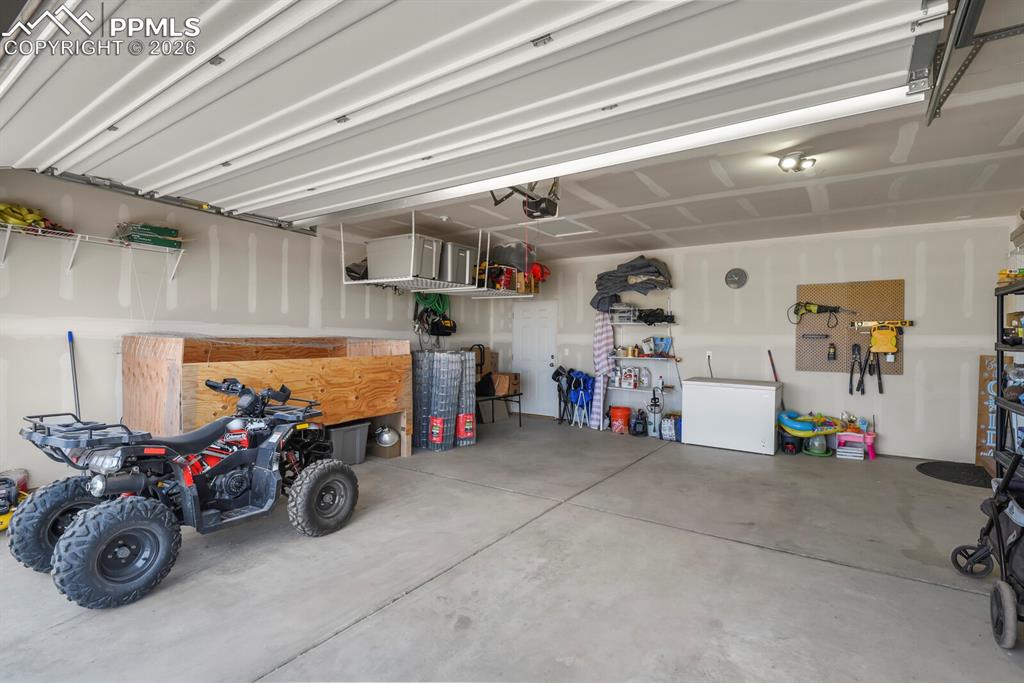 Image 34 of 48: Spacious garage with concrete flooring and exposed ceiling beams