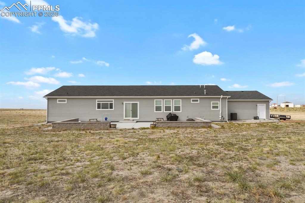Image 36 of 48: Rear exterior with gray siding, dark shingle roof, and multiple windows