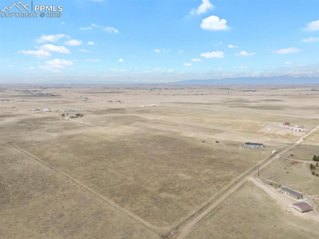Image 44 of 48: Expansive open terrain with distant mountain ranges and scattered residenti