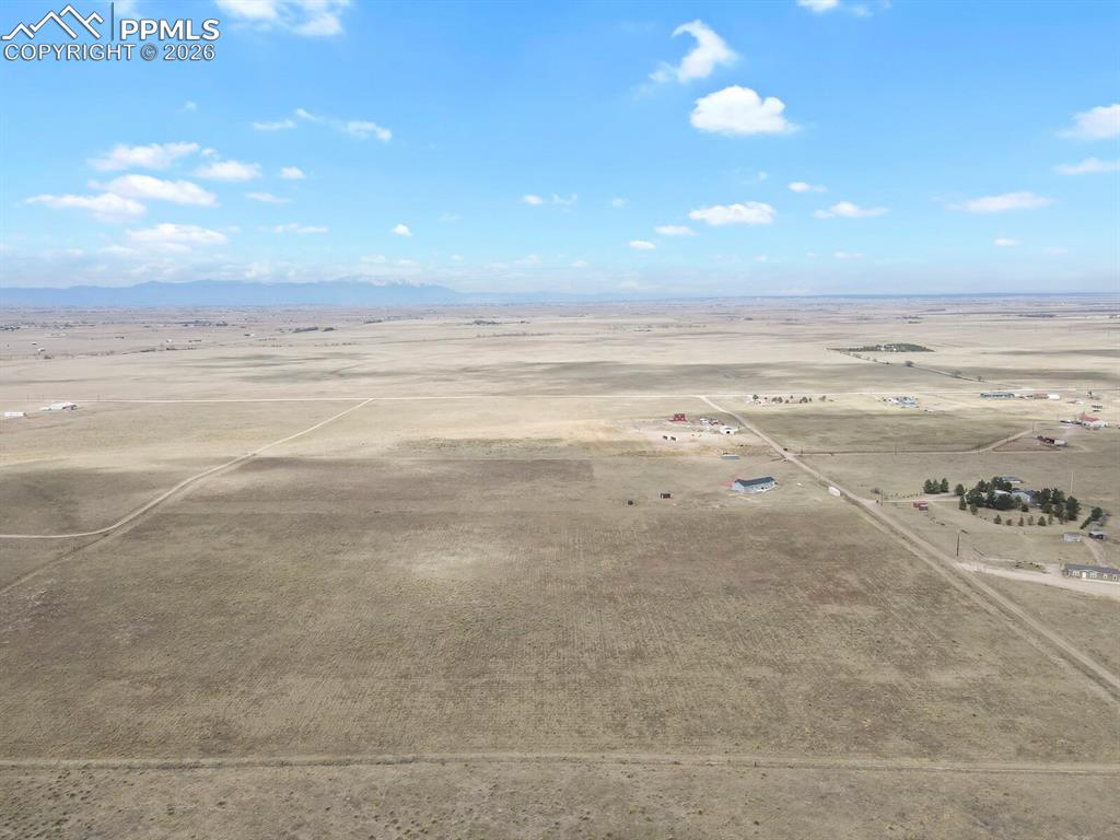 Image 45 of 48: Expansive undeveloped acreage with distant mountain ranges under a blue sky