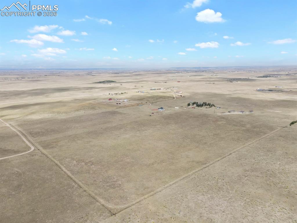 Image 46 of 48: Expansive open land featuring a clear perimeter, a visible dirt road, and d