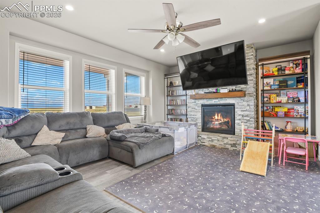 Image 7 of 48: Living room featuring a stone-clad fireplace with a wood mantel, recessed l