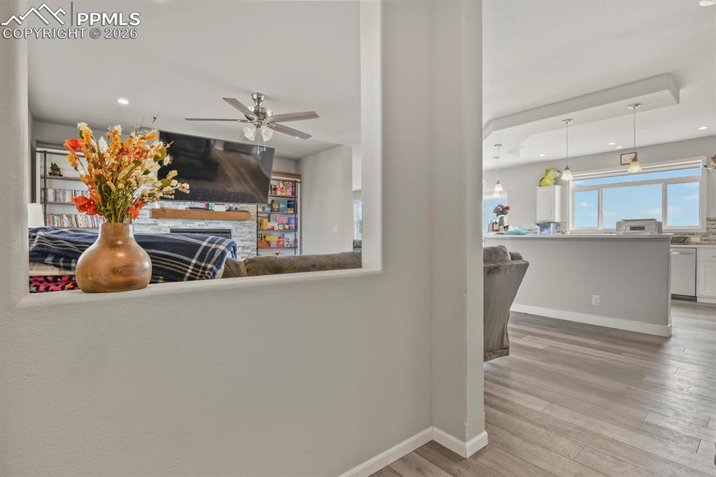 Image 8 of 48: Open-concept living area with wood-finish flooring, a stone-faced fireplace