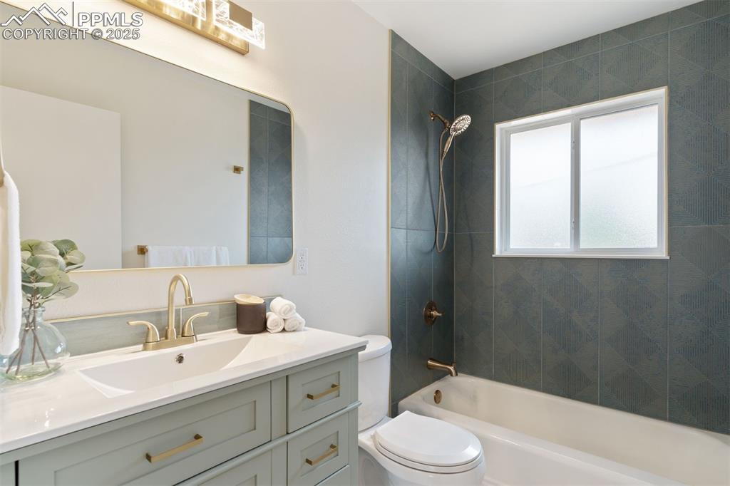 Image 5 of 37: Renovated bathroom, with new vanity, fixtures, tile and lighting.