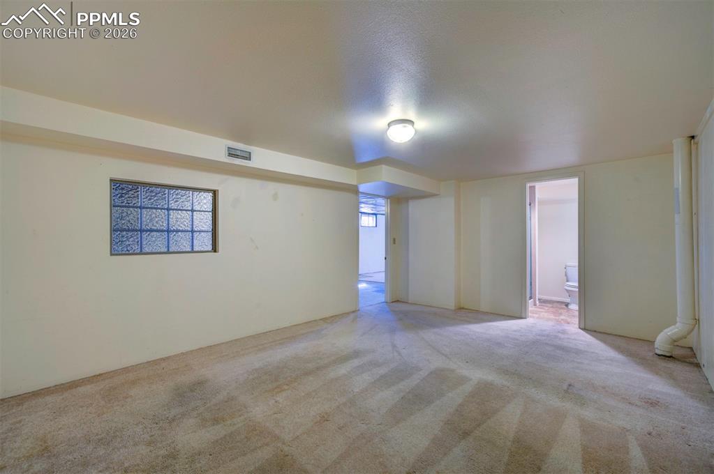 Image 29 of 40: Another view of non-conforming bedroom, with view to 3/4 bath and into open