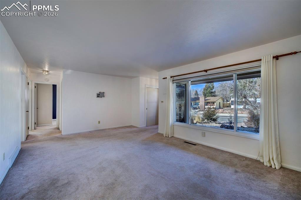 Image 4 of 40: Living room with large picture window; looking down hallway to bedrooms