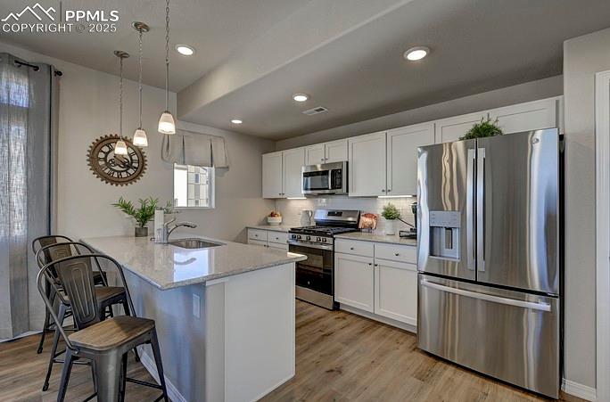 Image 10 of 21: Kitchen featuring appliances with stainless steel finishes, a kitchen bar, 