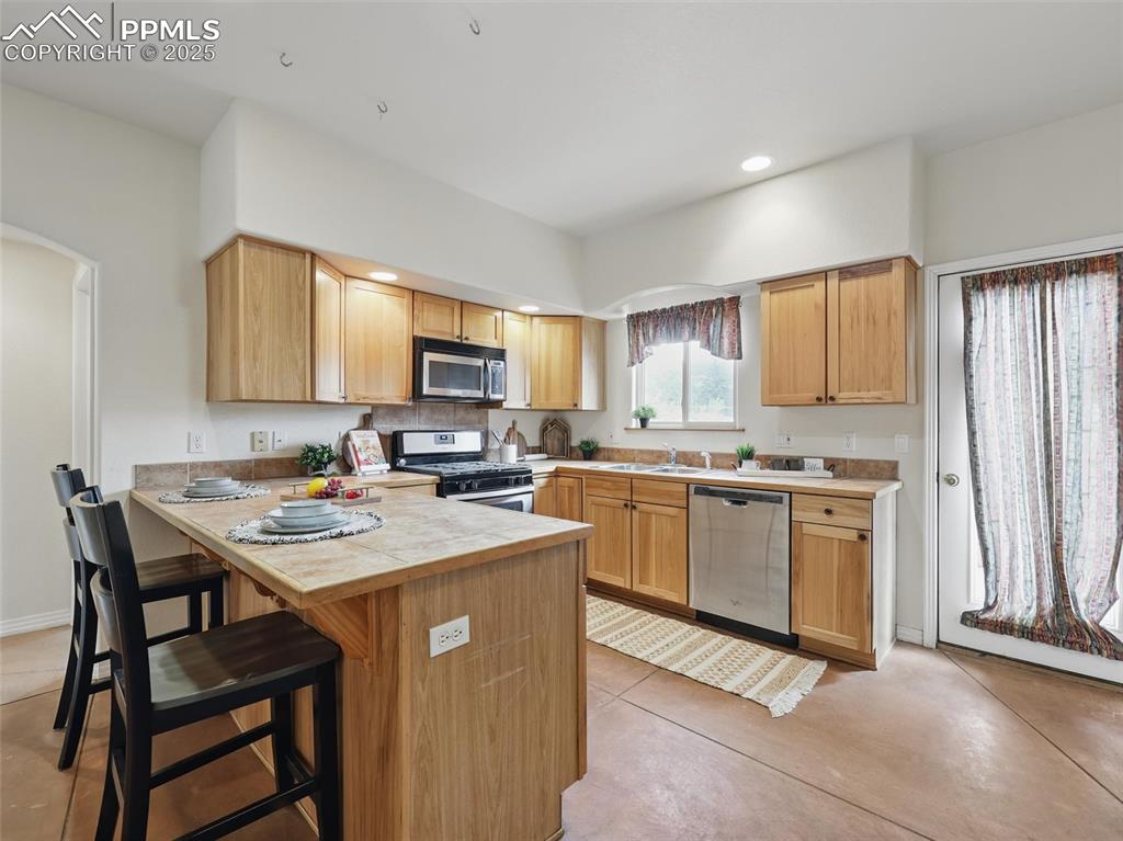 Image 9 of 41: Kitchen with appliances with stainless steel finishes, a breakfast bar area