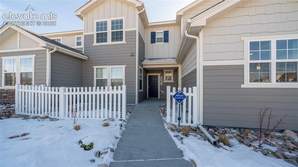 Caption: Modern townhouse exterior featuring multi-toned siding, white trim, a concrete walkway, and a white 