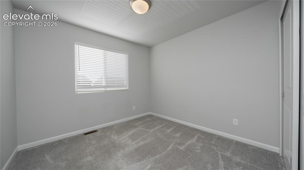Image 11 of 13: Neutral gray walls with white trim and gray carpeting