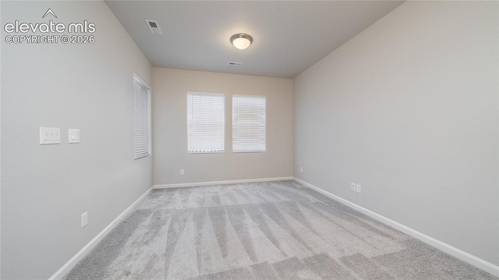 Image 3 of 13: Carpeted room featuring multiple windows with blinds, light gray walls, a f