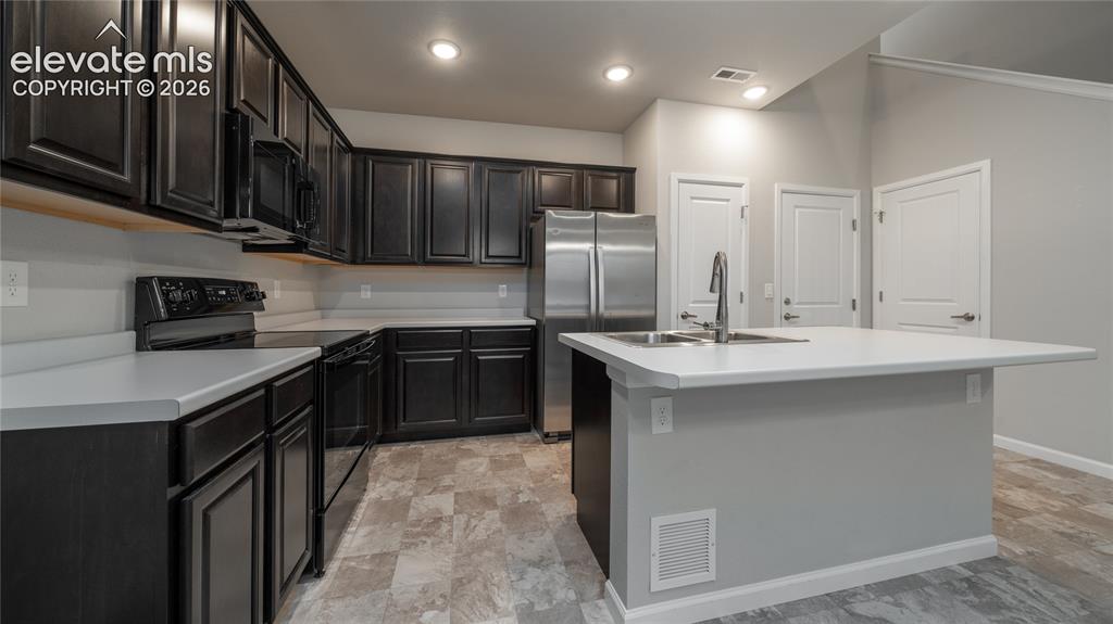 Image 4 of 13: Contemporary kitchen featuring dark wood-finish cabinetry, stainless steel 