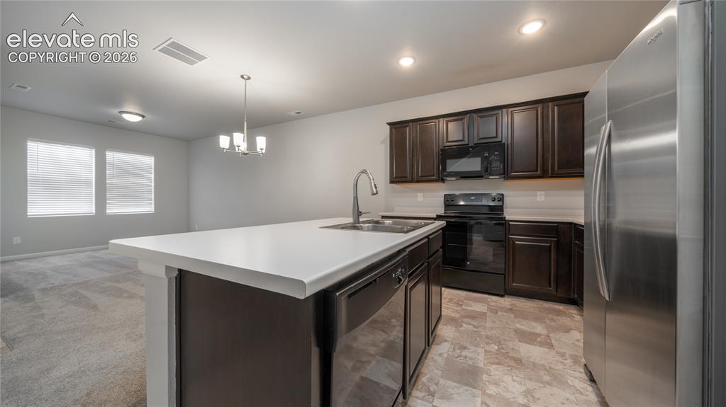 Image 5 of 13: Modern kitchen featuring dark wood cabinetry, stainless steel appliances, a