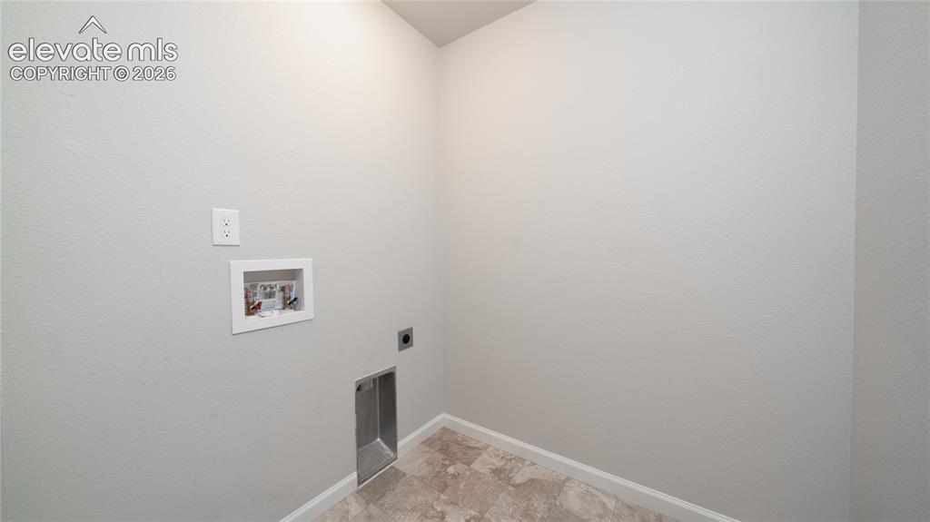 Image 7 of 13: Utility space featuring light gray walls, an electrical outlet, and a laund