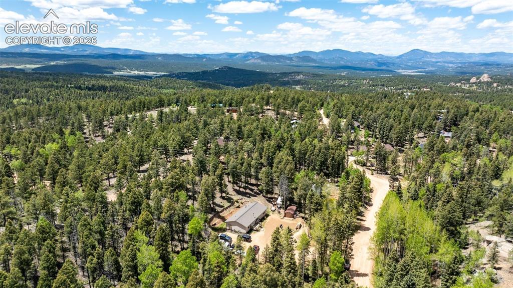 Image 35 of 36: Expansive treed property with natural terrain and distant mountainous lands
