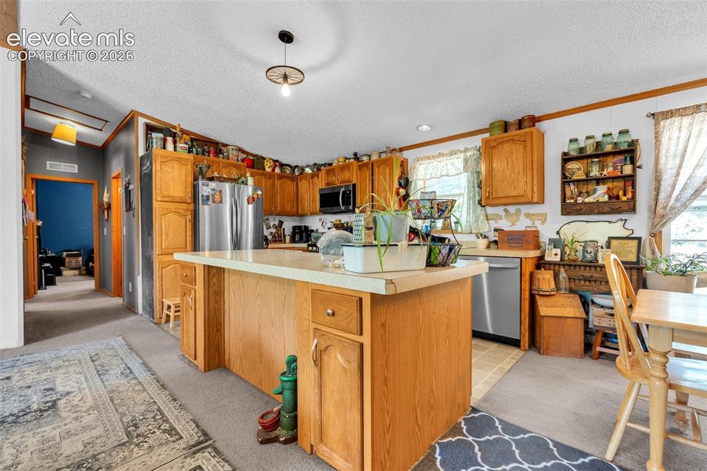 Image 6 of 36: Kitchen featuring light wood cabinetry and a central island with a light-co