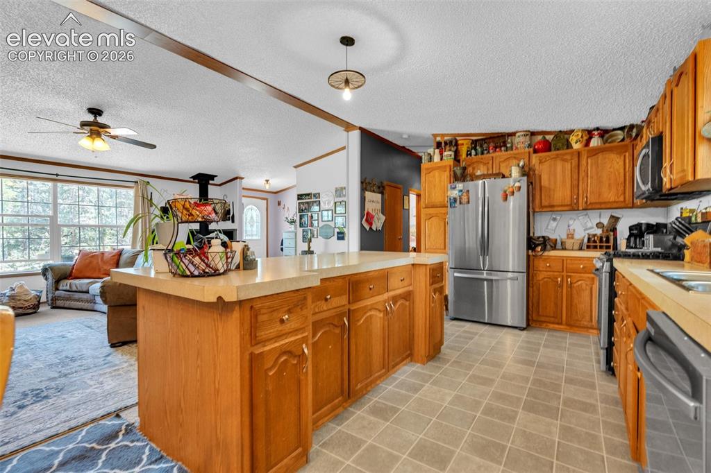 Image 8 of 36: Spacious kitchen featuring light wood cabinetry, a central island with coun