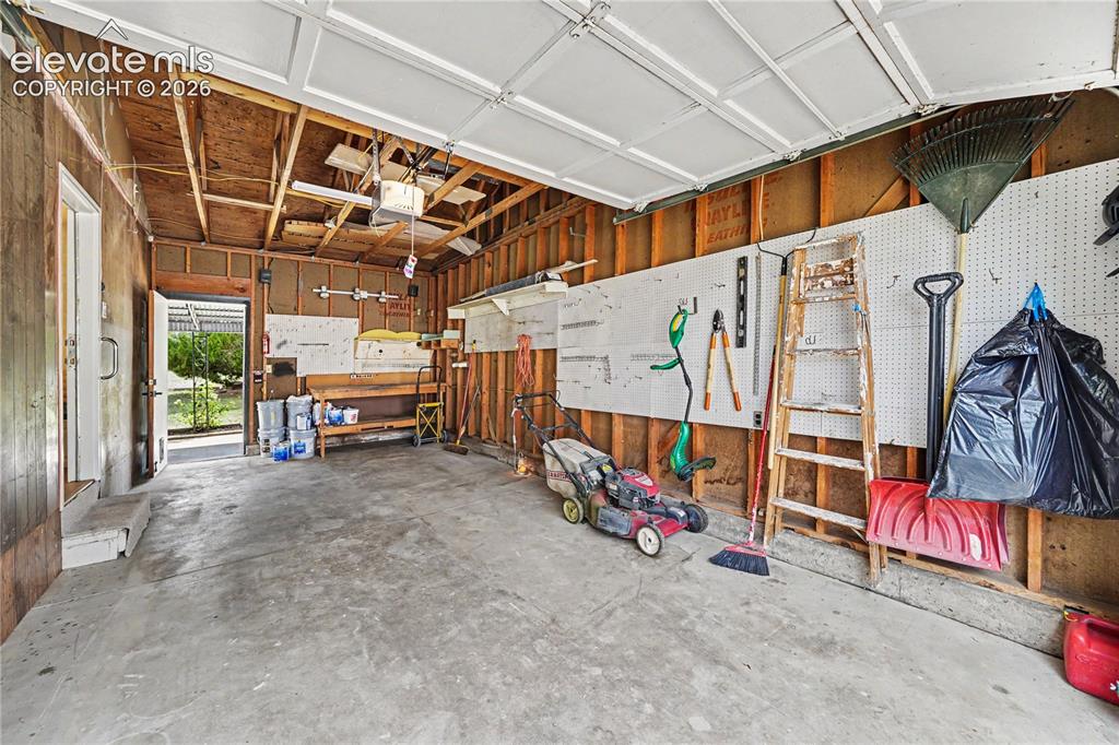 Image 13 of 22: One Car attached garage with small shop area.  Walkout to back patio.