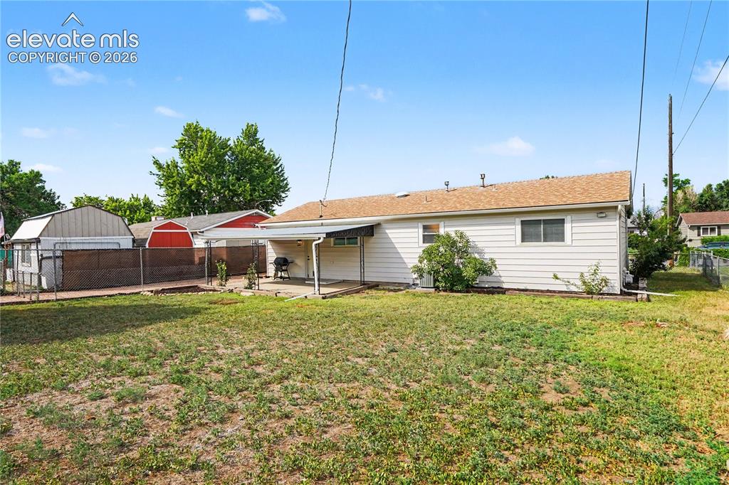 Image 14 of 22: Expansive backyard featuring a covered patio, chain-link fencing.