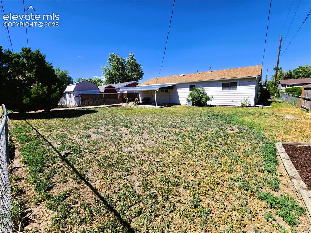 Image 14 of 18: Expansive backyard featuring a chain-link fence boundary and dog run side y