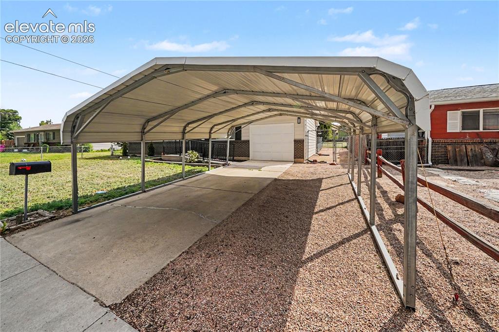 Image 17 of 22: Expansive carport structure featuring a concrete driveway and gravel ground